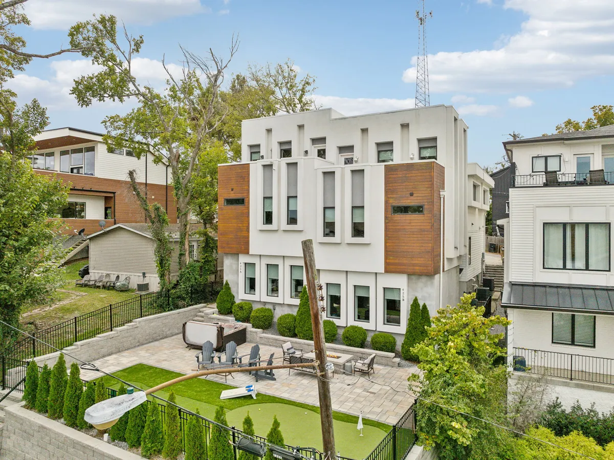 A beautifully landscaped backyard featuring a modern outdoor seating area, a green lawn for playtime, and a contemporary home façade. The scene is inviting, sunlit, and offers spaces for both group activities and quiet moments, with visual cues suggesting family-friendly and pet-friendly outdoor living.