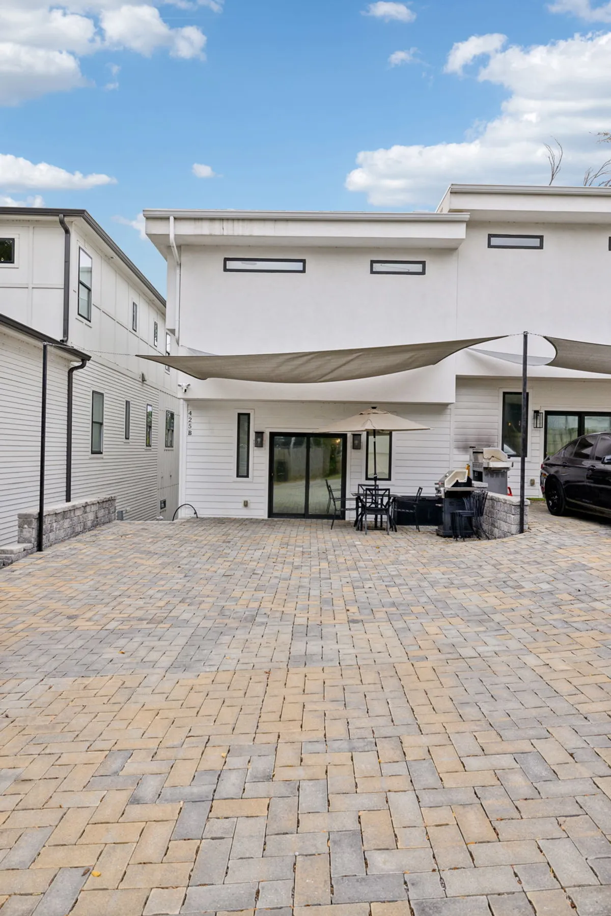 A view of the paved patio area featuring modern architecture, an outdoor dining set, and a car parked nearby—hinting at easy, free parking. The patio is ready for meals or gatherings, and the visible car links the image to the amenity of free parking for guests.