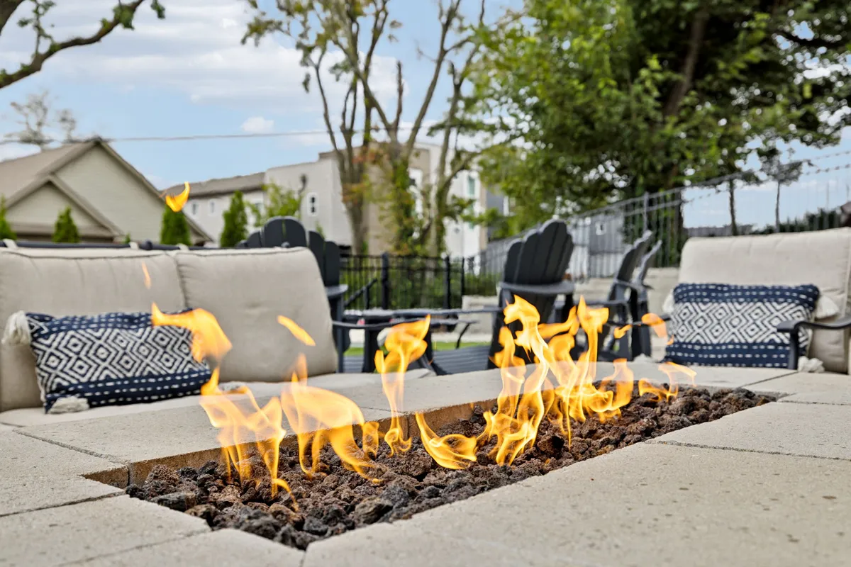 A cozy outdoor fire pit surrounded by comfortable seating with colorful decorative pillows. The scene invites guests to unwind, share stories, or make s'mores as the sun sets, enhancing the sense of camaraderie and relaxation after an exciting night out.
