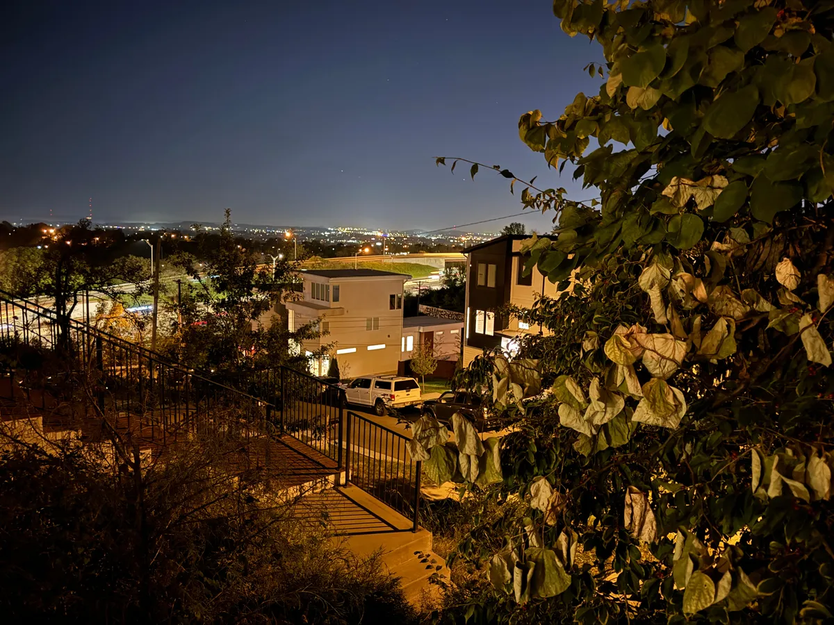 A tranquil view with modern homes, a backdrop of distant city lights, and foliage in the foreground. The peaceful evening atmosphere suggests easy access to Nashville’s urban energy while offering a serene retreat from the excitement.